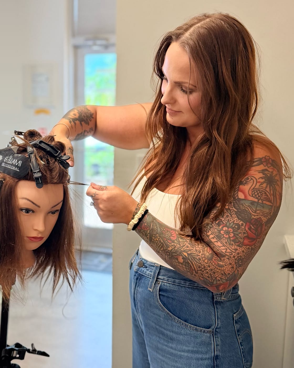 Alli Canterbury sectioning hair on a Bellami practice head with a tail comb during the Bellami Master Class