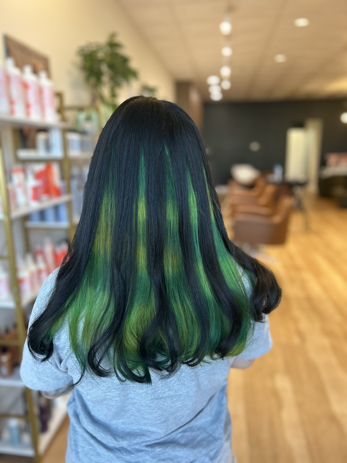 Emerald green peekaboo color under jet-black hair, seen from behind