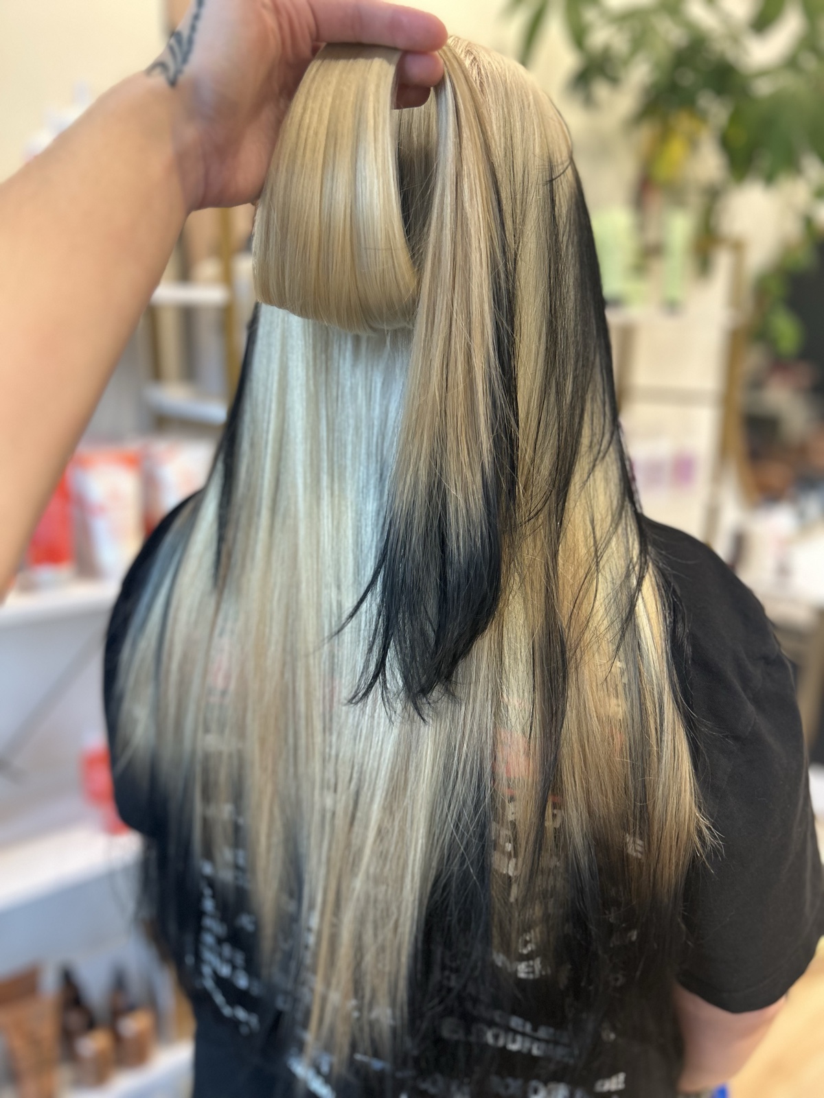 Long straight hair split between icy platinum, golden blonde and jet black, the top section lifted to show black panels underneath. Creative color by Tori Knox at Canterbury & Co. Salon in Fort Myers
