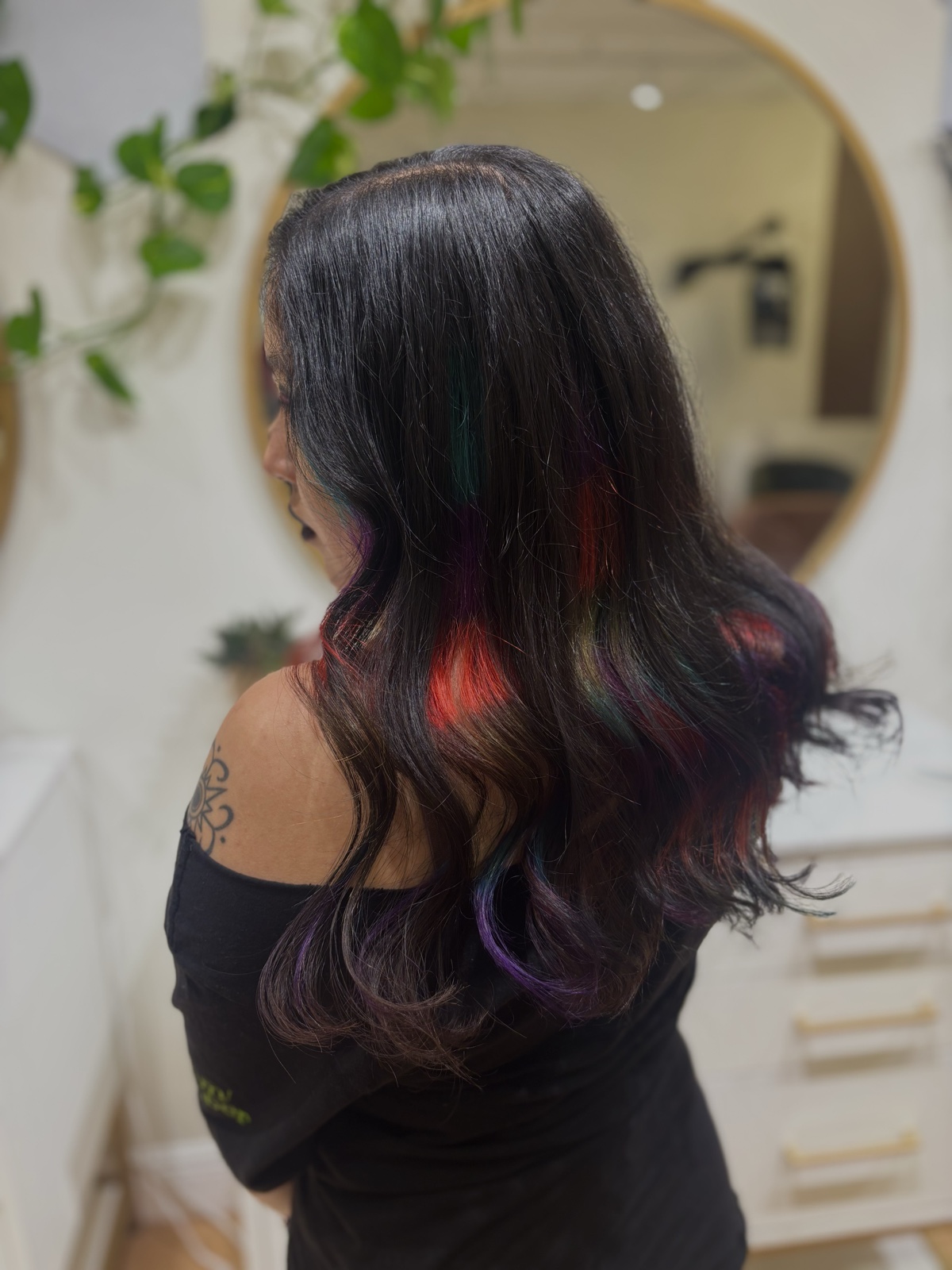 Long dark waves with hidden panels of red, green, teal and purple showing through as the hair moves, seen from behind. Vivid color at Canterbury & Co. Salon in Fort Myers