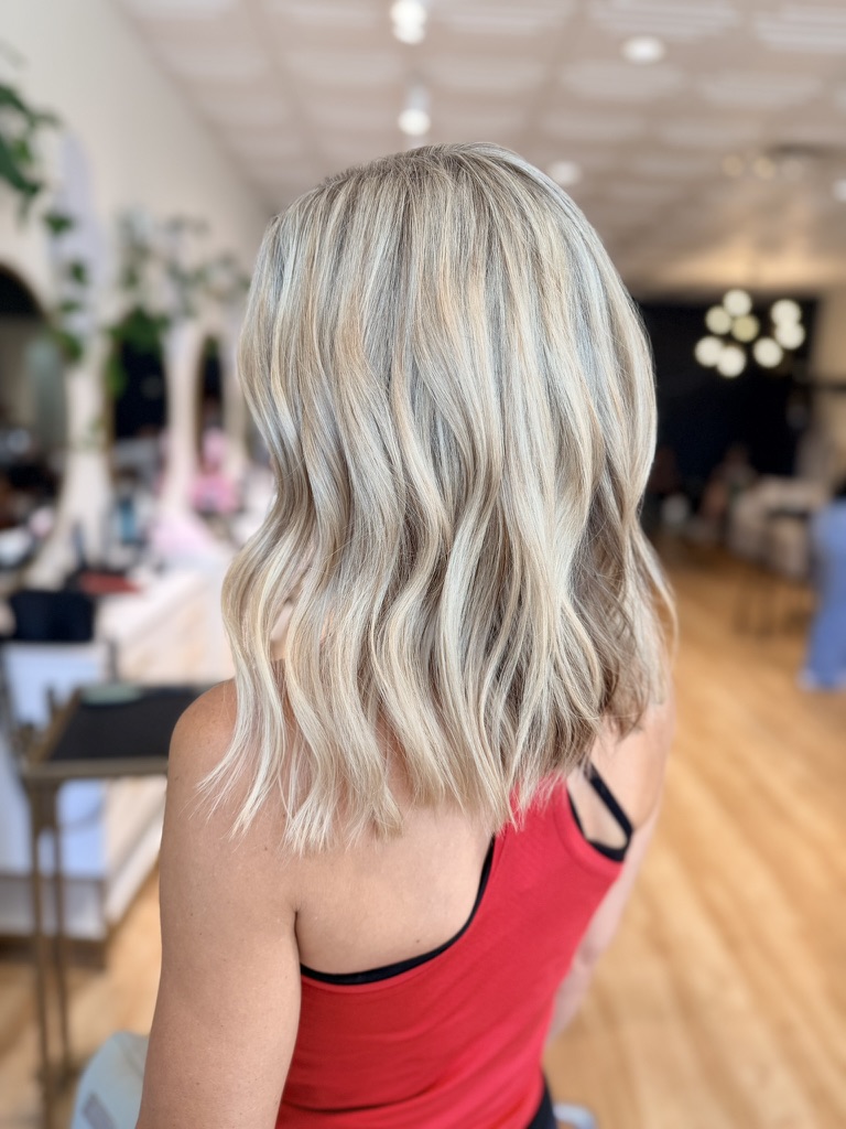 Creamy blonde full-dimension color in soft textured waves, seen from behind