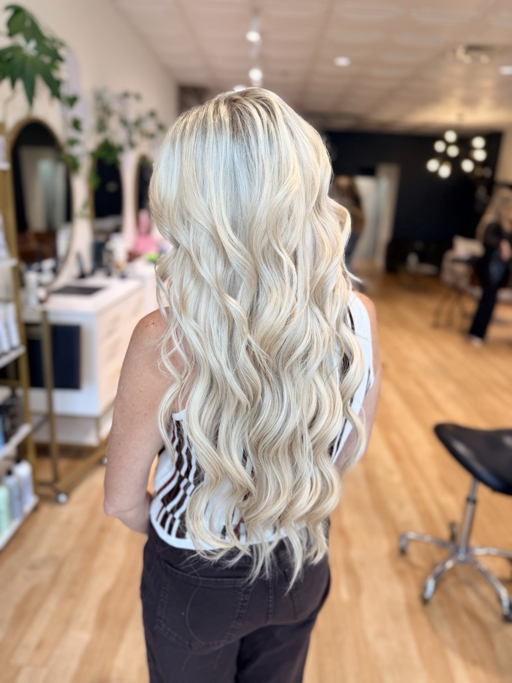 Long, full blonde hair extensions styled in soft waves, seen from behind