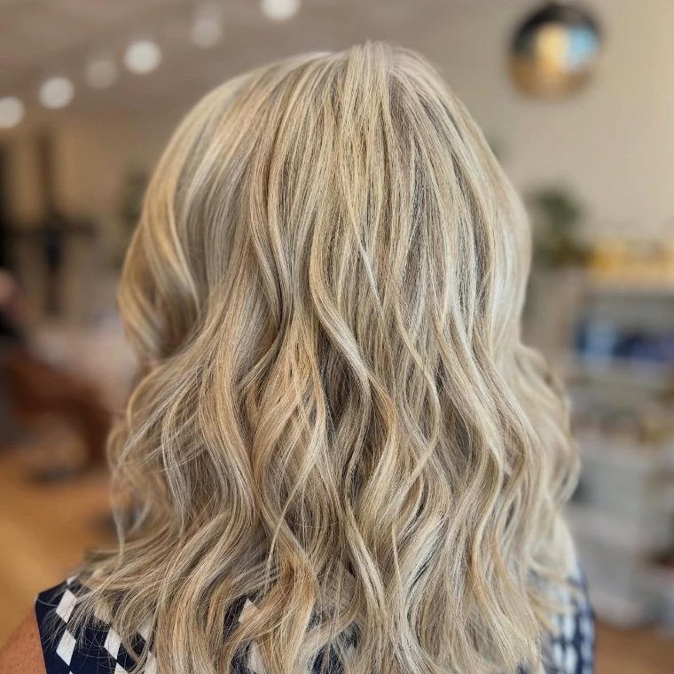 Cool beige-blonde balayage in textured waves, toned deliberately cool to resist Gulf-sun brassiness