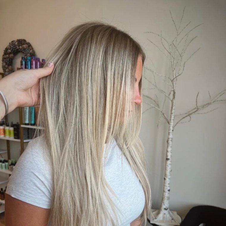 Creamy blonde hair with brighter face-framing dimension, worn long and sleek