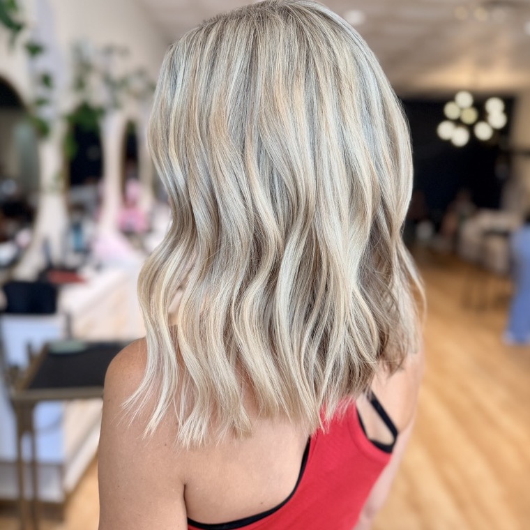Creamy blonde full-dimension color in soft textured waves, seen from behind