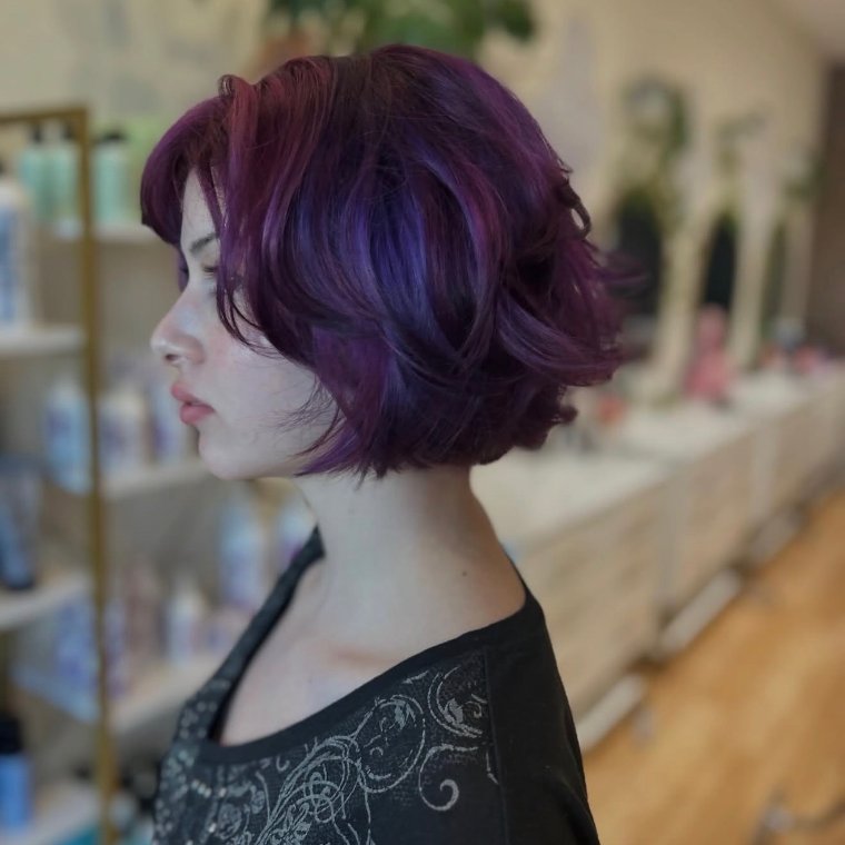 Deep violet-purple fashion color on a chin-length textured bob, in profile