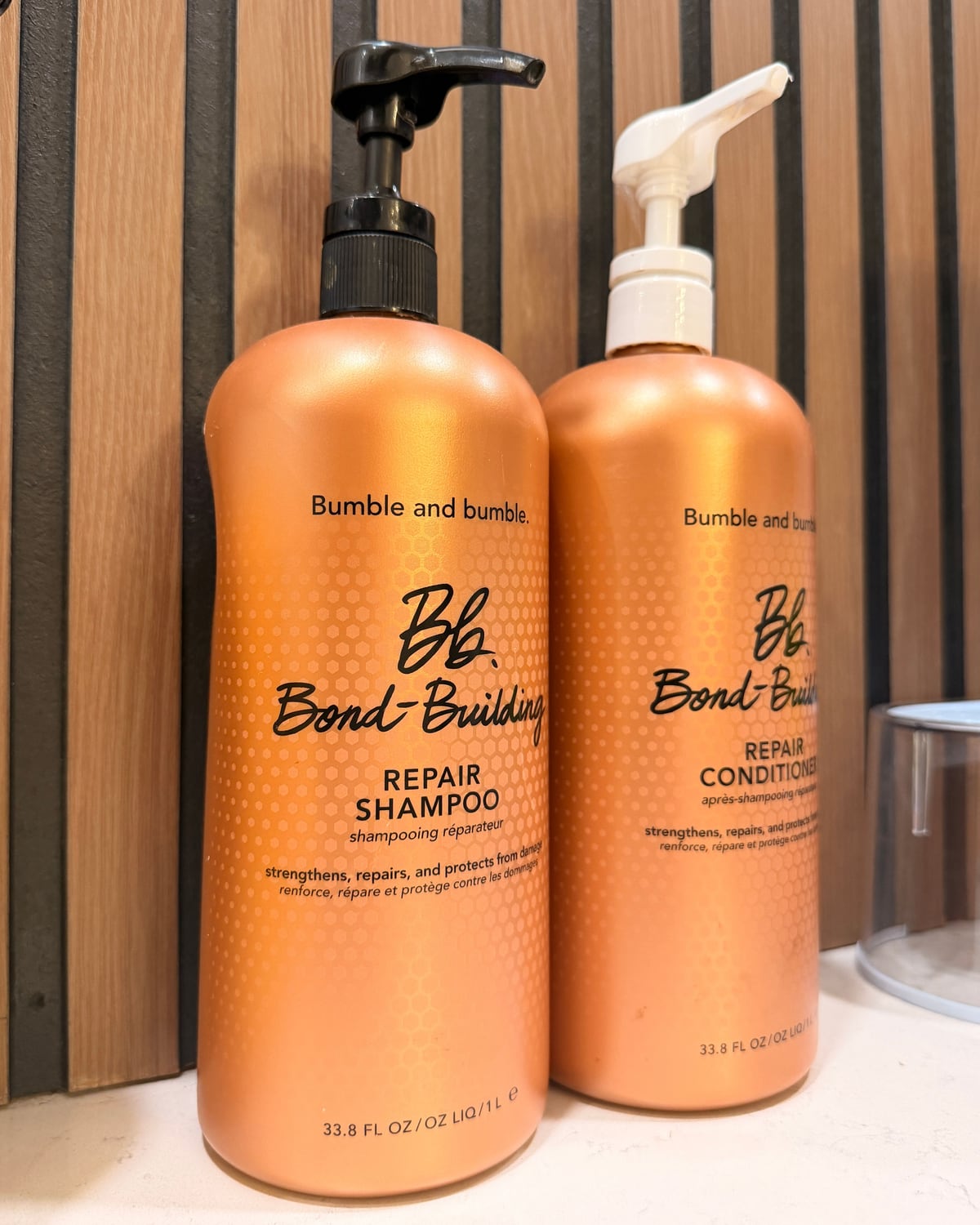 Bumble and bumble Bond-Building Repair Shampoo and Conditioner in large salon pump bottles, on the shelf at Canterbury & Co. in Gulf Coast Town Center, Fort Myers.