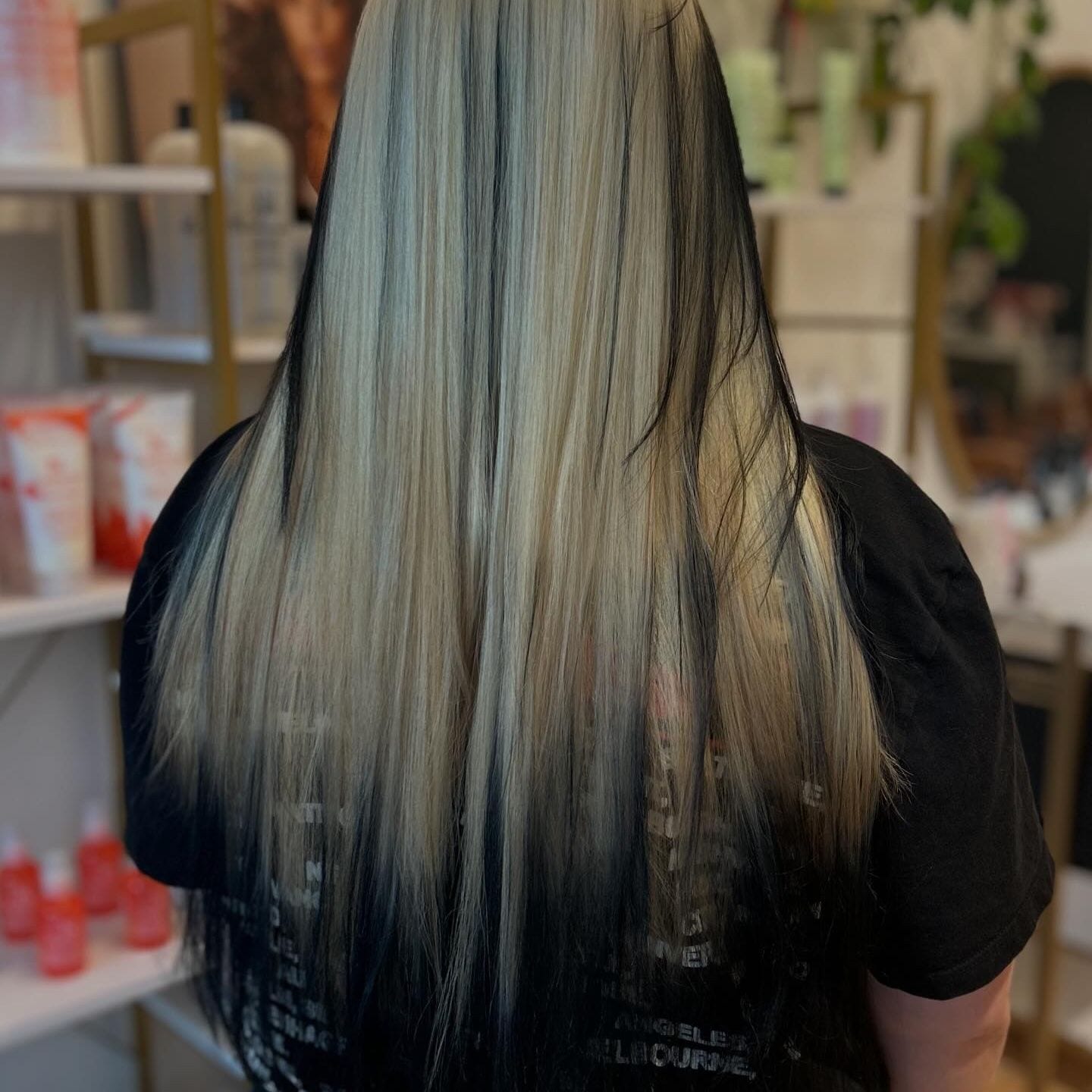 After color correction: the same long hair lifted to a bright, cool blonde with black panels underneath, seen from behind at Canterbury & Co. in Fort Myers