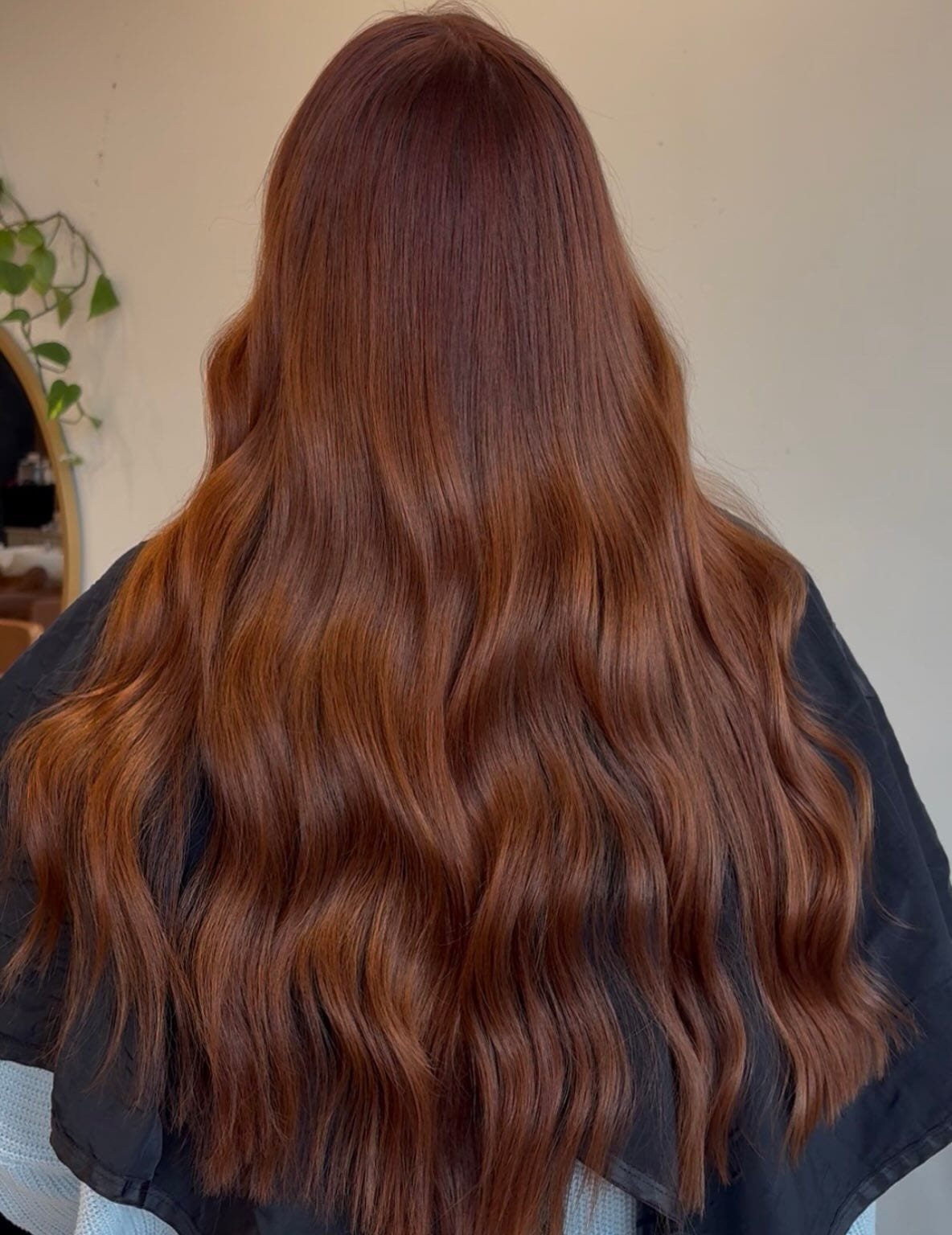 Long hair in a rich copper color with loose waves, seen from behind at Canterbury & Co. in Fort Myers