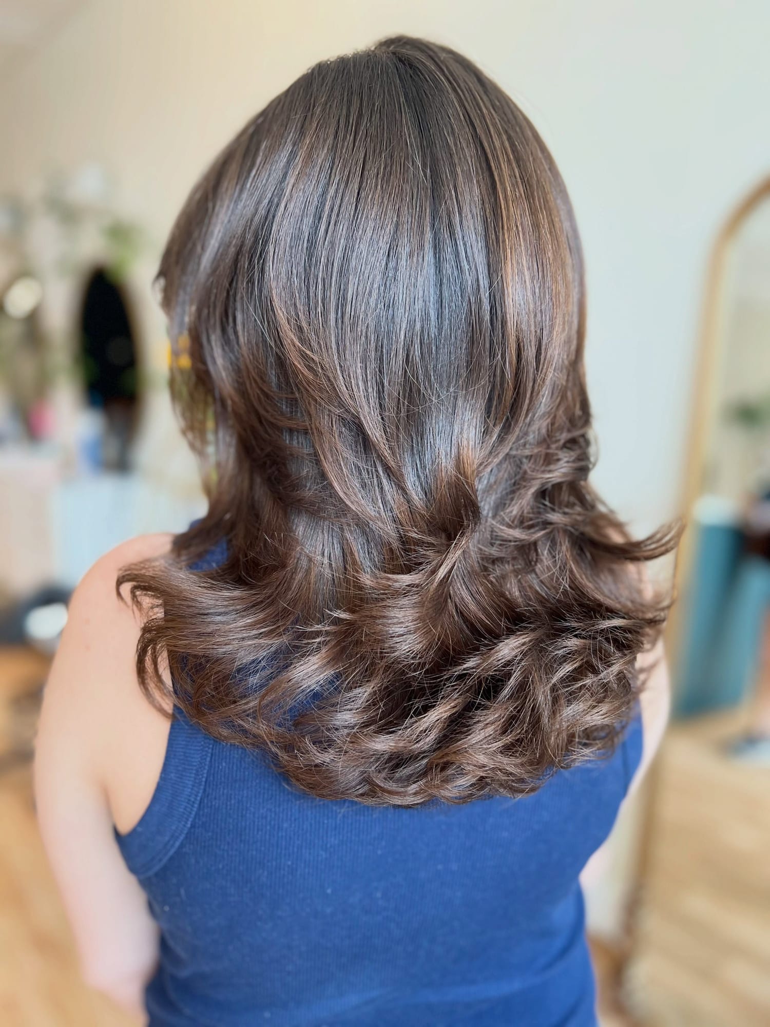 Shoulder-length brunette hair freshly cut and blown out with full, curled-under layers, seen from behind at Canterbury & Co. in Fort Myers