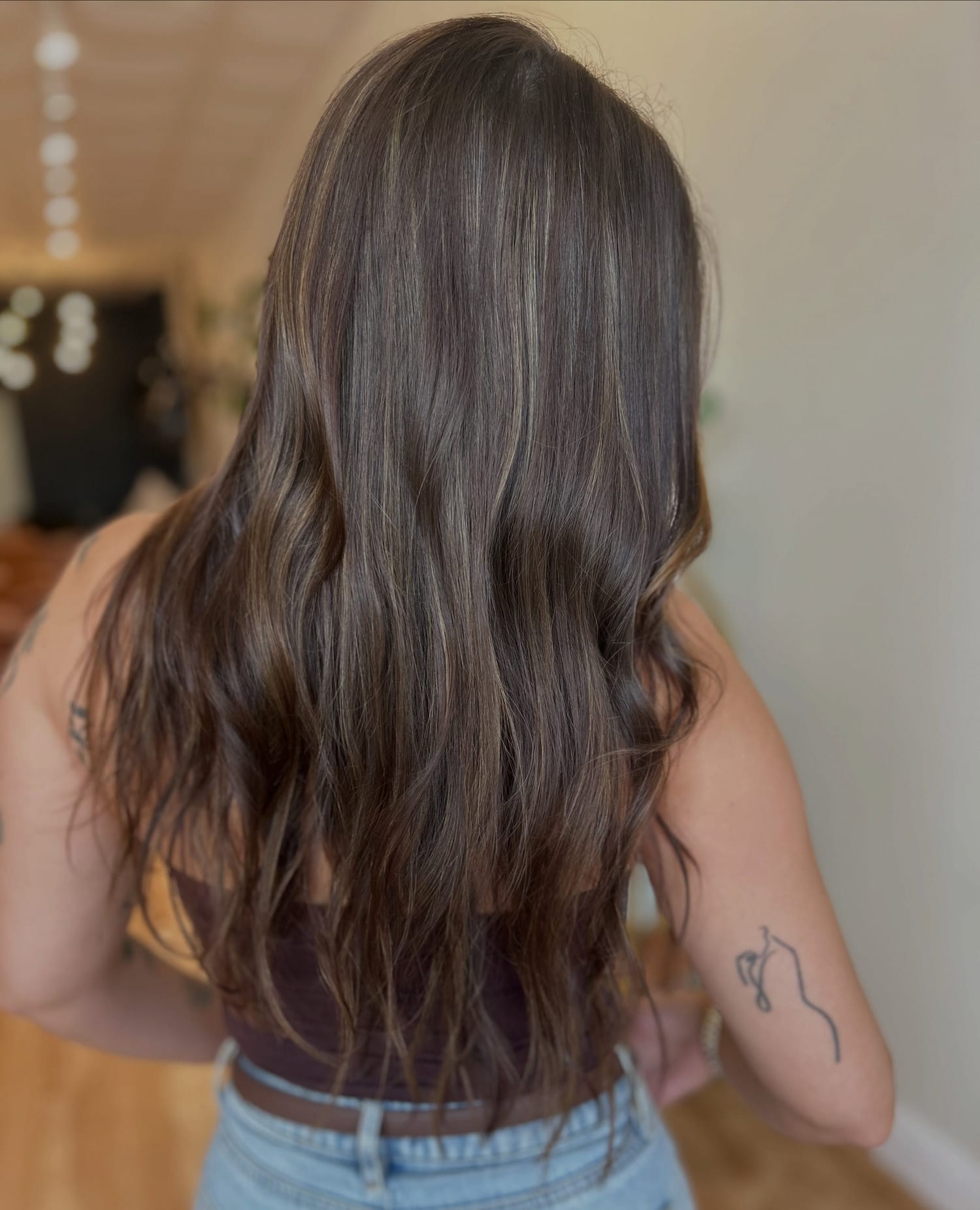 Long dark brunette hair with K-tip extensions and soft dimension, worn in loose waves, seen from behind
