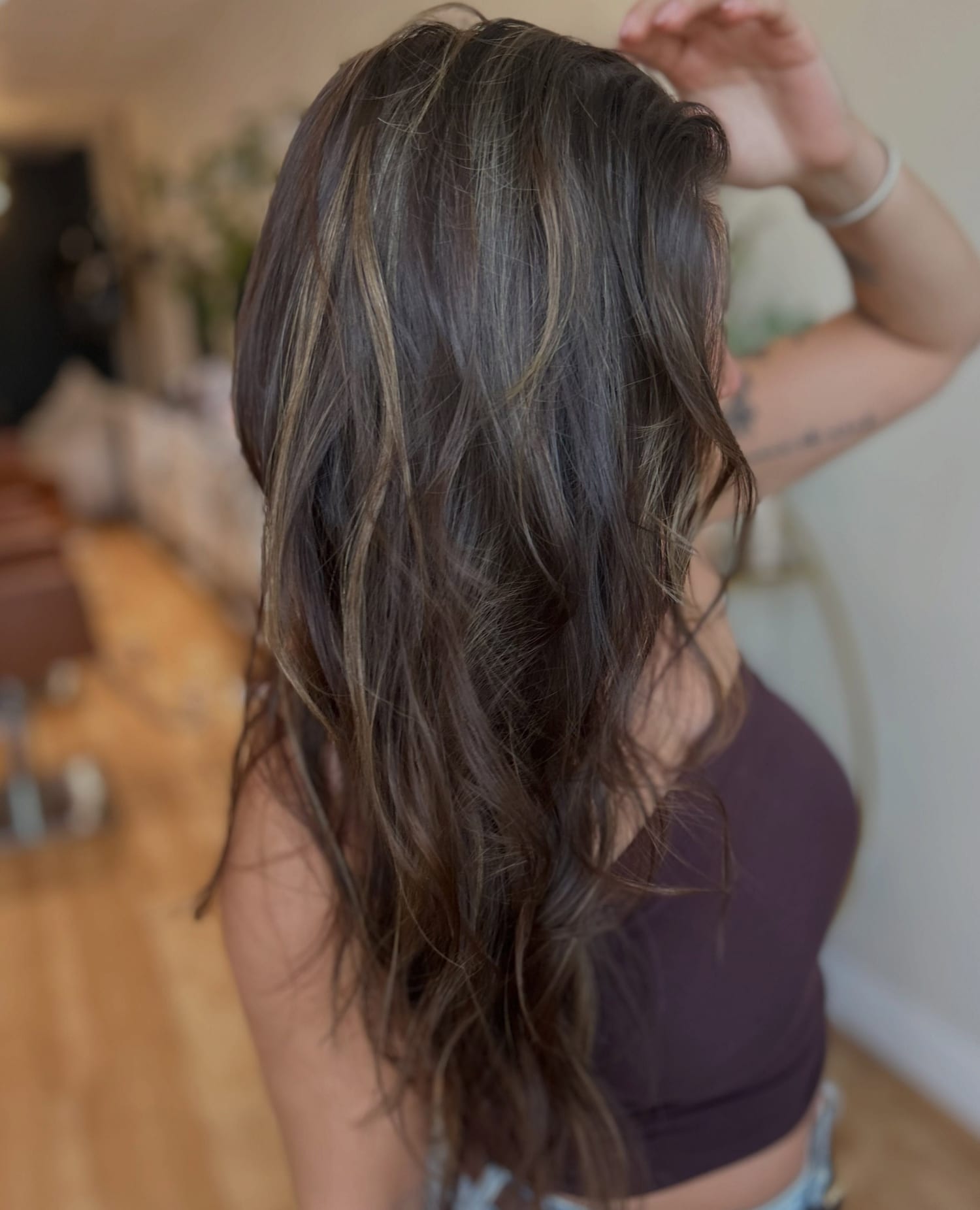 The same dark brunette K-tip result from the side, tousled, with lighter pieces through the lengths